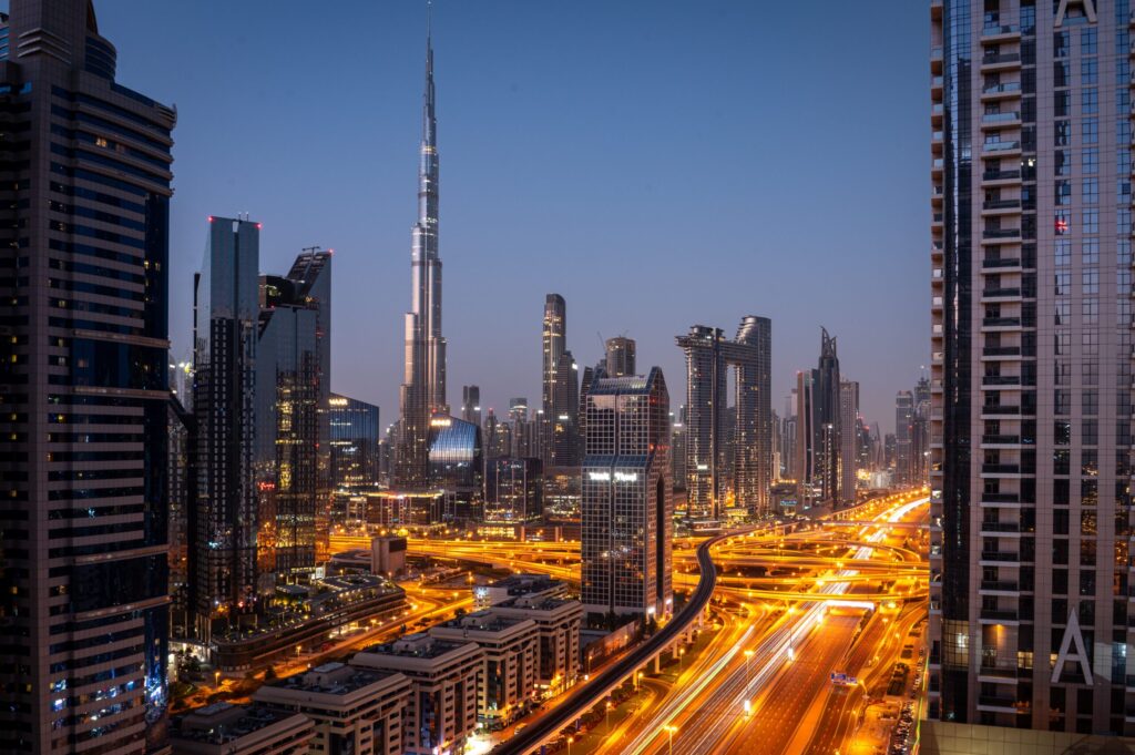 Downtown Dubai skyline at dusk with the Burj Khalifa illuminated and highway light trails
