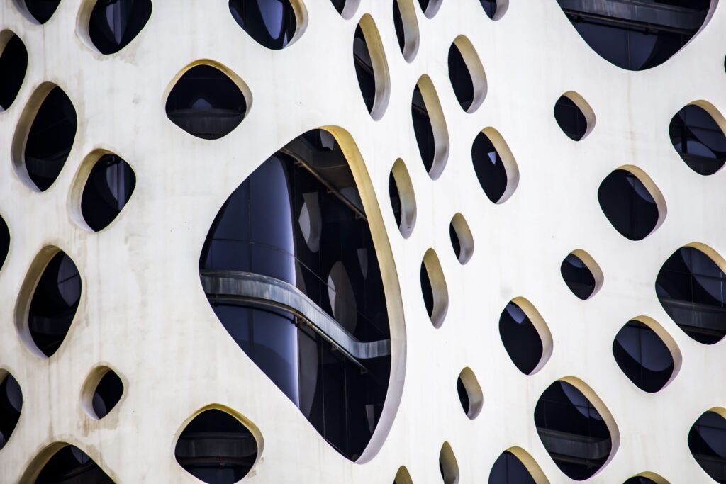 Extreme close-up of a Business Bay building's perforated concrete honeycomb facade with oval cutouts
