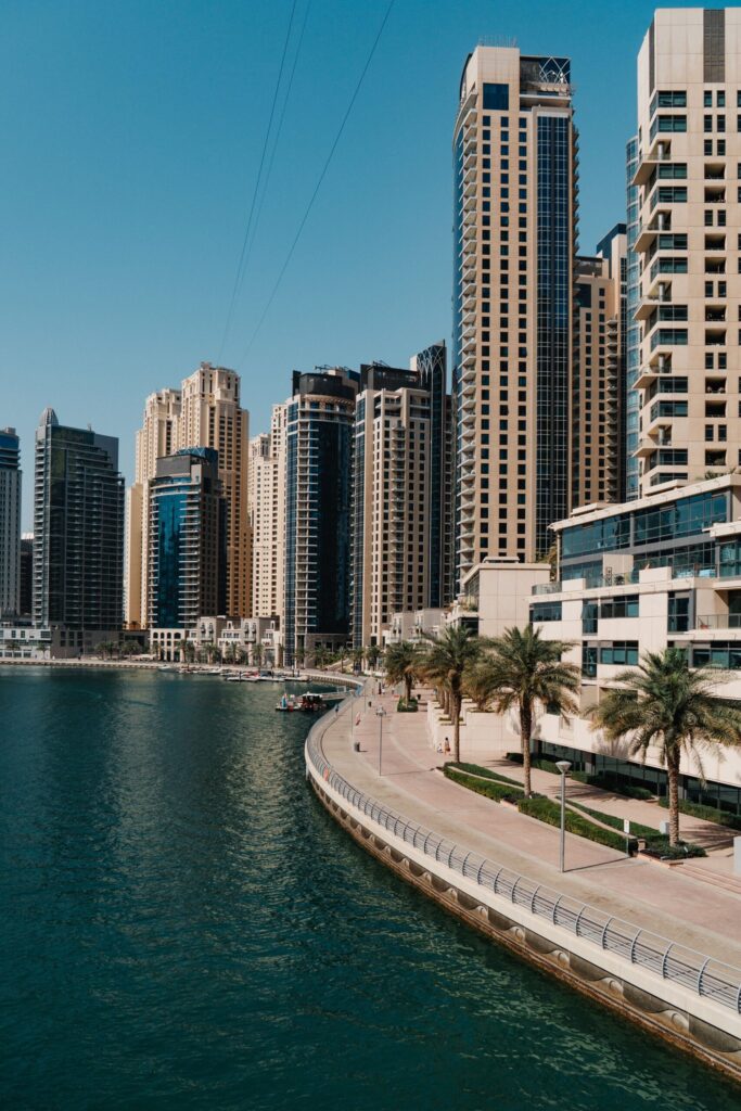 Dense cluster of beige residential high-rise towers with balconies along a curved waterfront promenade