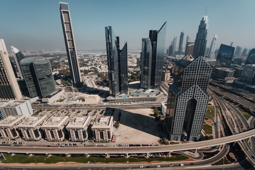 Aerial daytime view of a dense Dubai high-rise district along a major highway corridor, representative of Business Bay's tower skyline