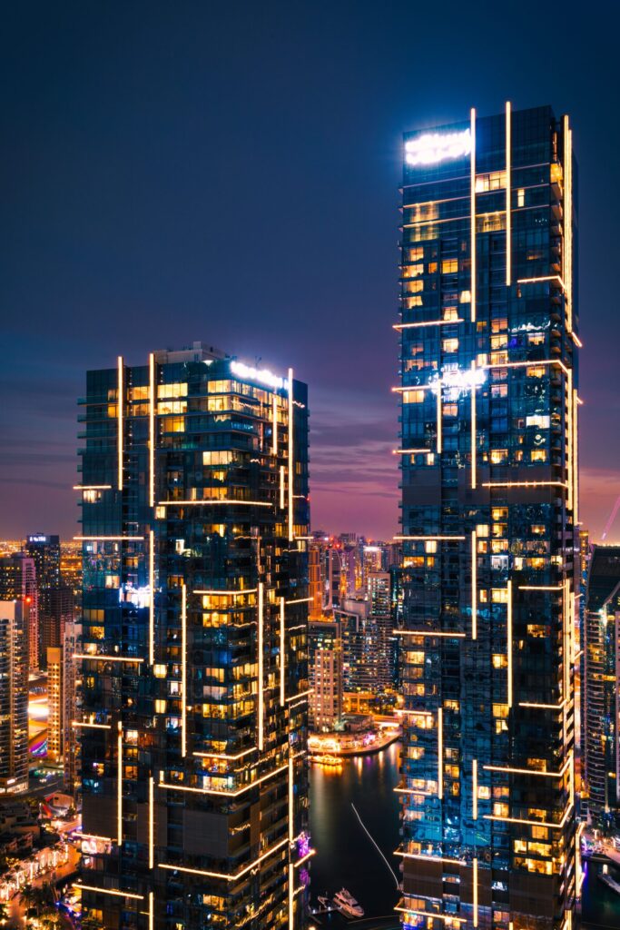 Illuminated Dubai Marina towers at night with LED facade lighting reflected in the water