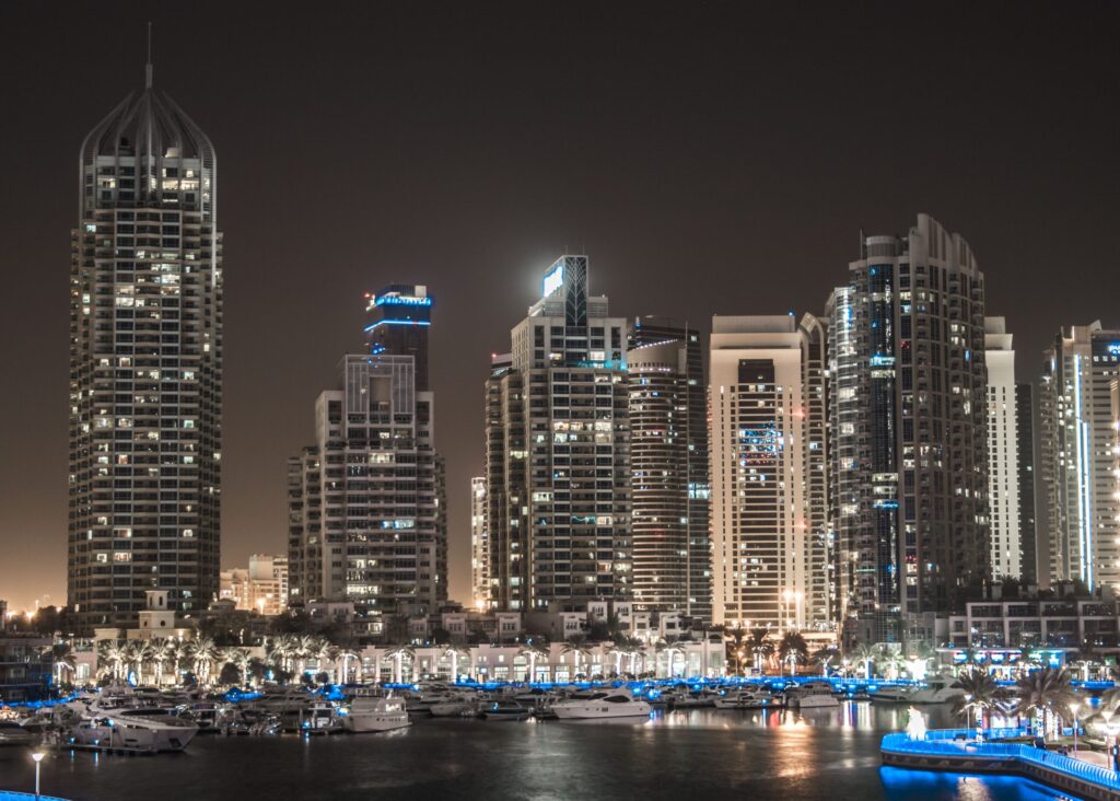 Night view of illuminated Dubai Marina apartment towers reflected in the calm yacht basin water