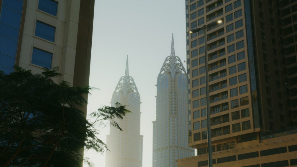 Low-angle view of twin Dubai towers with ornate white lattice spire crowns at sunrise
