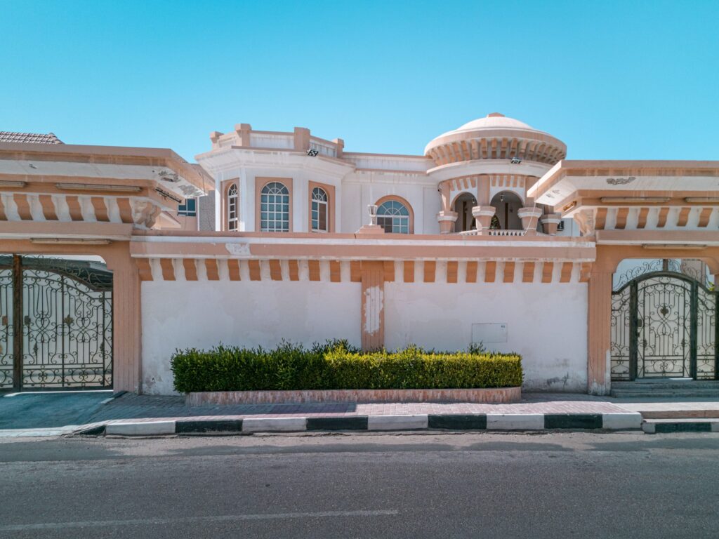 Ornate villa with a domed corner turret and decorative wrought-iron gate in a Dubai villa community