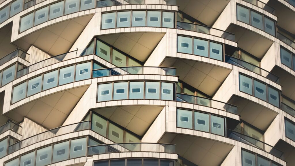 Close-up of a modern residential skyscraper with a distinctive repeating angular balcony pattern, matching Binghatti's contemporary design language