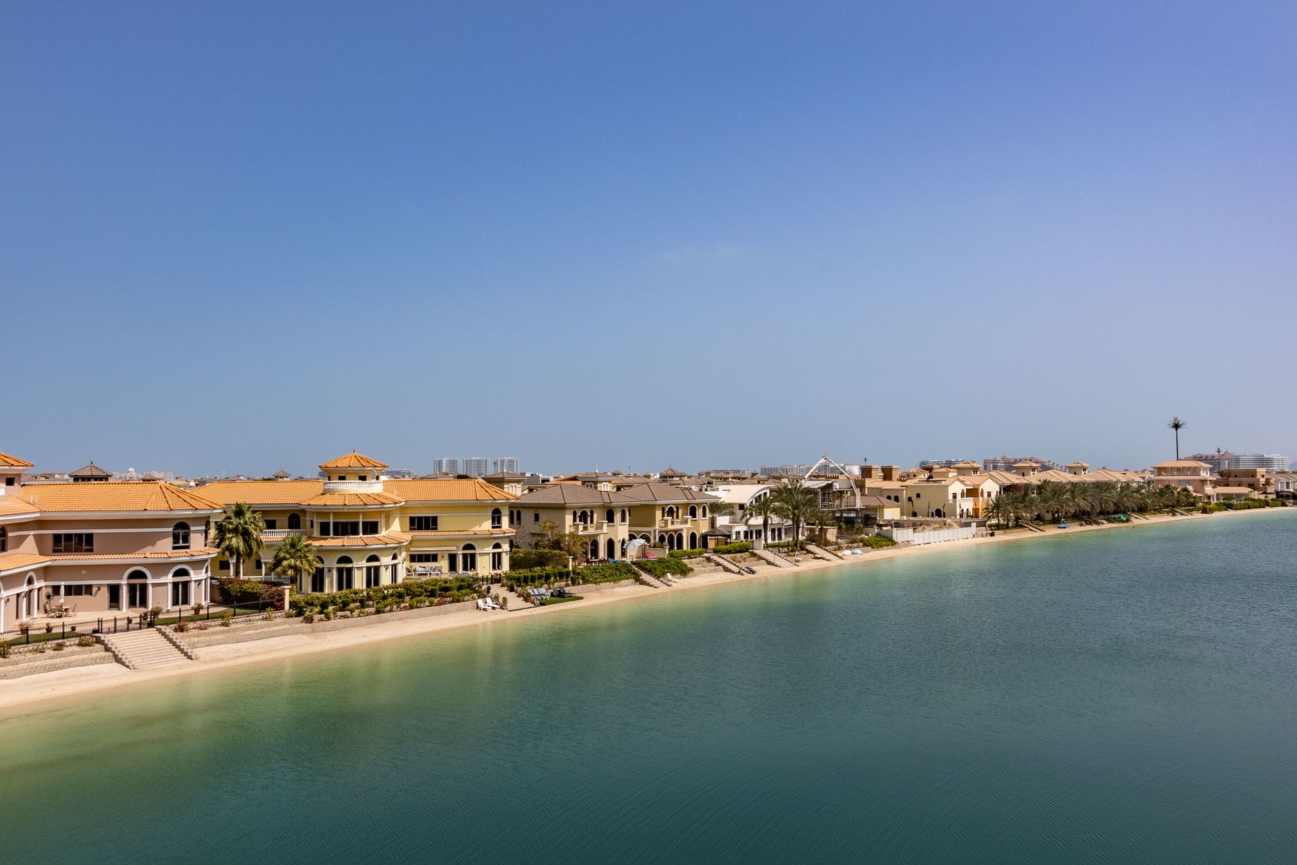 Aerial view of Signature Villas along a Palm Jumeirah frond, terracotta roofs and private beach frontage on the turquoise lagoon, Dubai