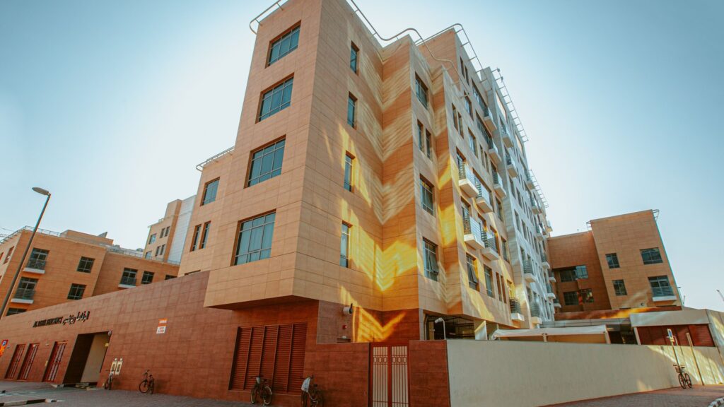 Low-angle view of a modern mid-rise apartment building with warm sandstone facade in Dubai