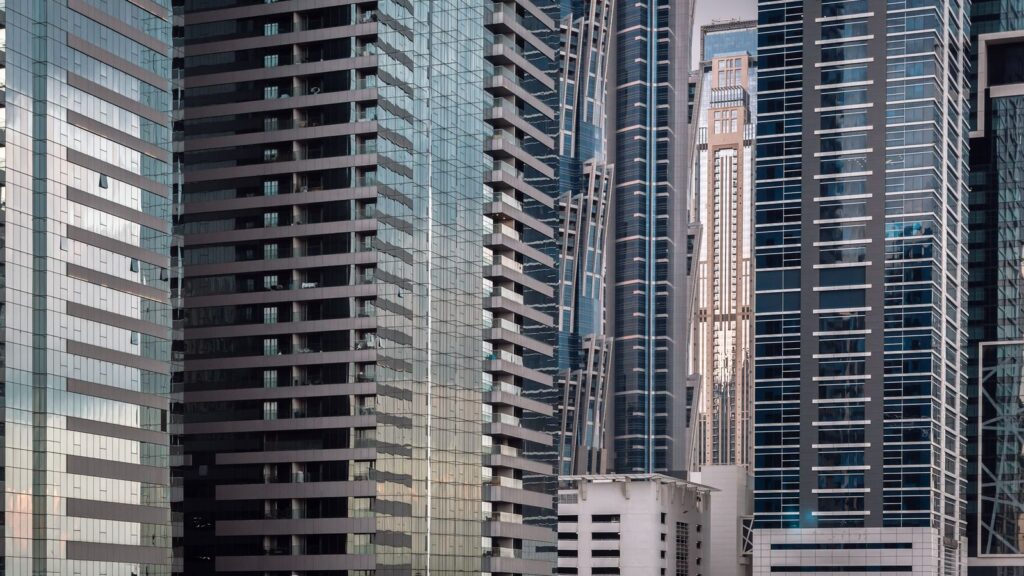 Low-angle view of clustered modern Dubai skyscrapers with glass and concrete facades under a clear sky, representing The Scala Tower's dense high-rise Business Bay setting