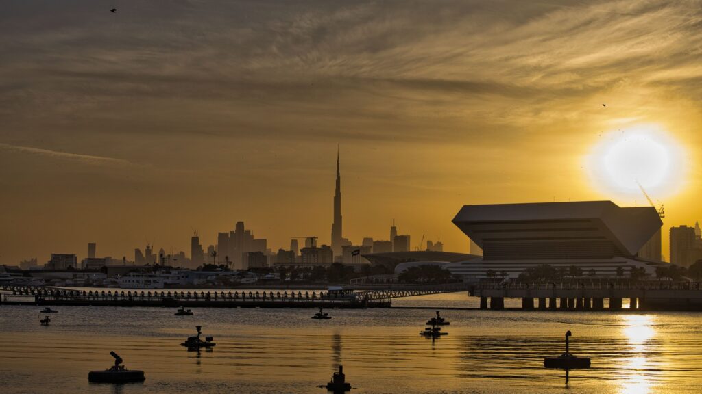 Dubai skyline silhouette at sunset with the Burj Khalifa visible above the waterfront