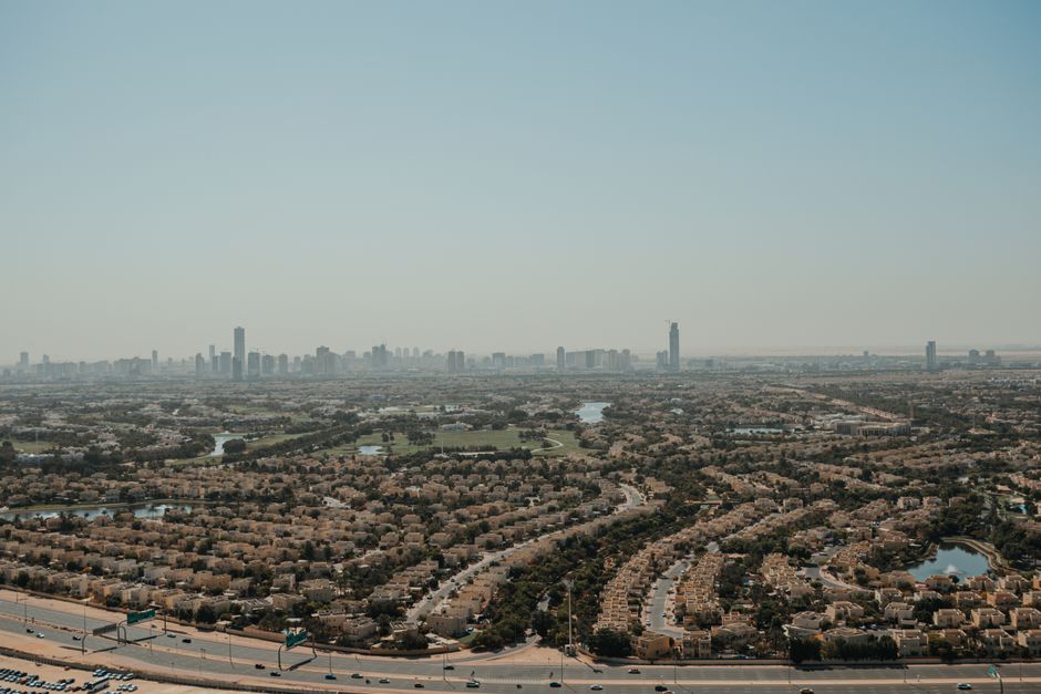 Aerial view of a low-density Dubai residential community with distant city skyline