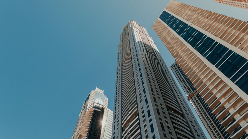Low-angle view of modern high-rise towers against a clear blue sky in Dubai