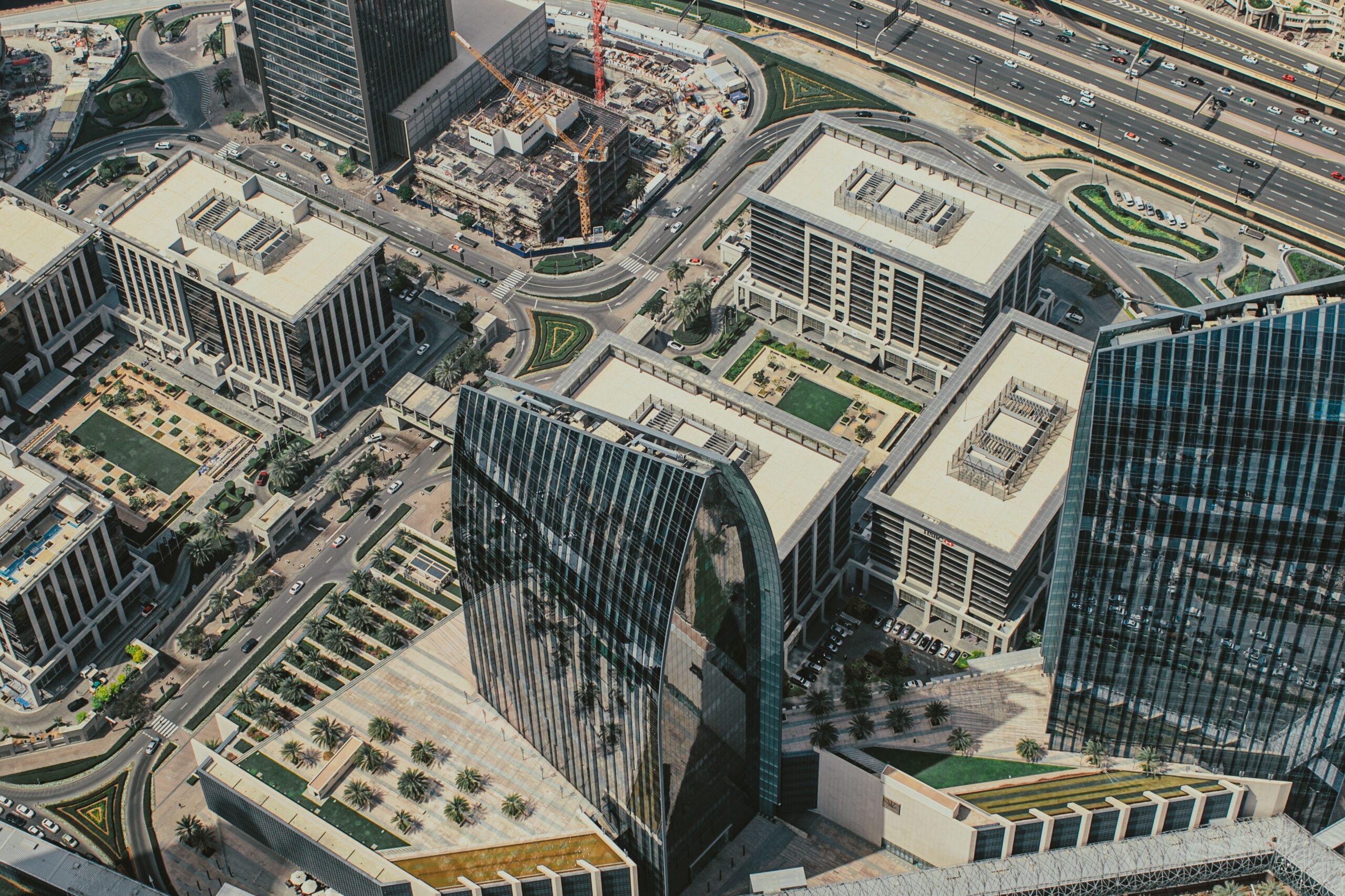 Aerial view of a modern Dubai business district with a curved glass tower