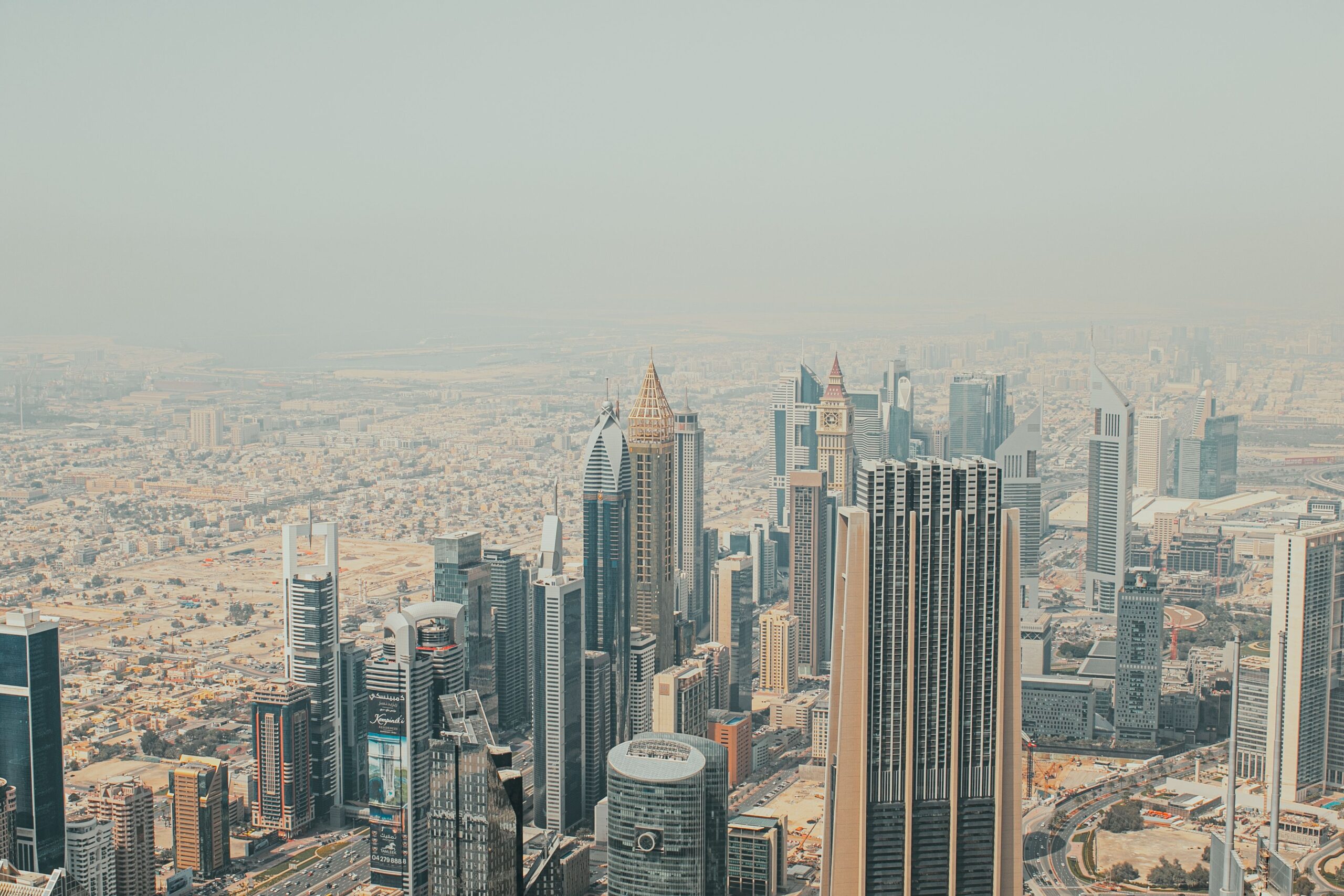 Hazy aerial view of Dubai residential and commercial towers along a main road, near Arjan and Al Barsha South