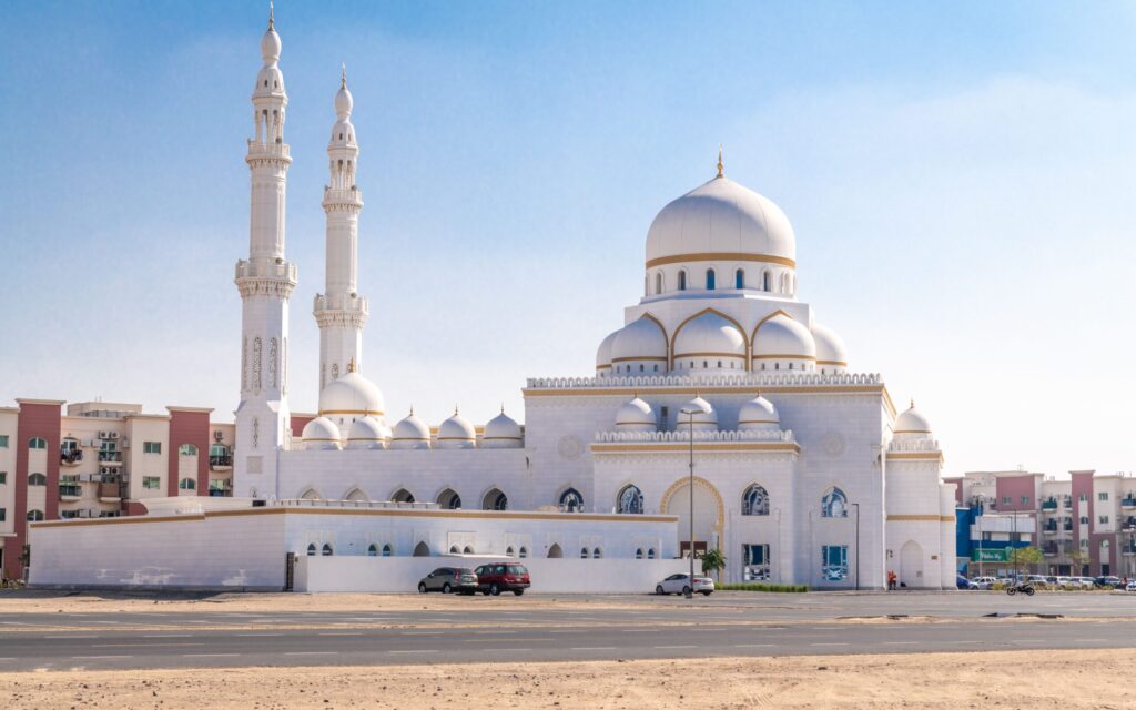 White mosque with detailed architecture under a clear sky in Dubai