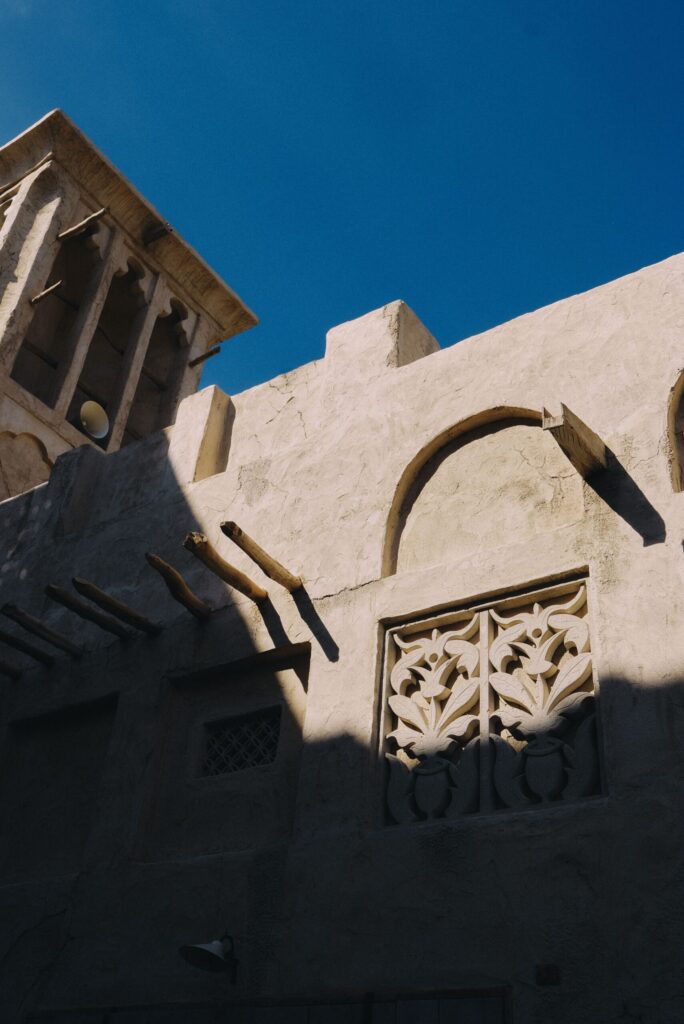 Sandstone Old Town-style low-rise building in Downtown Dubai with a traditional wind tower and carved arched window screen, near Miska 3