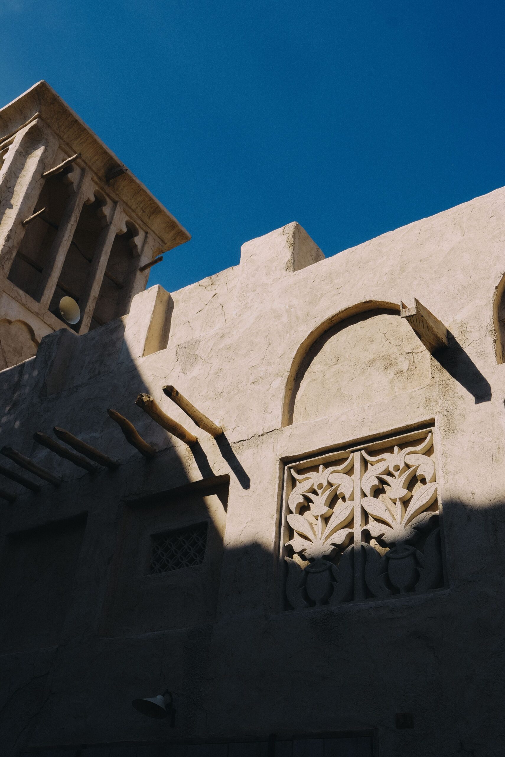 Sandstone Old Town-style low-rise building in Downtown Dubai with a traditional wind tower and carved arched window screen, near Miska 3