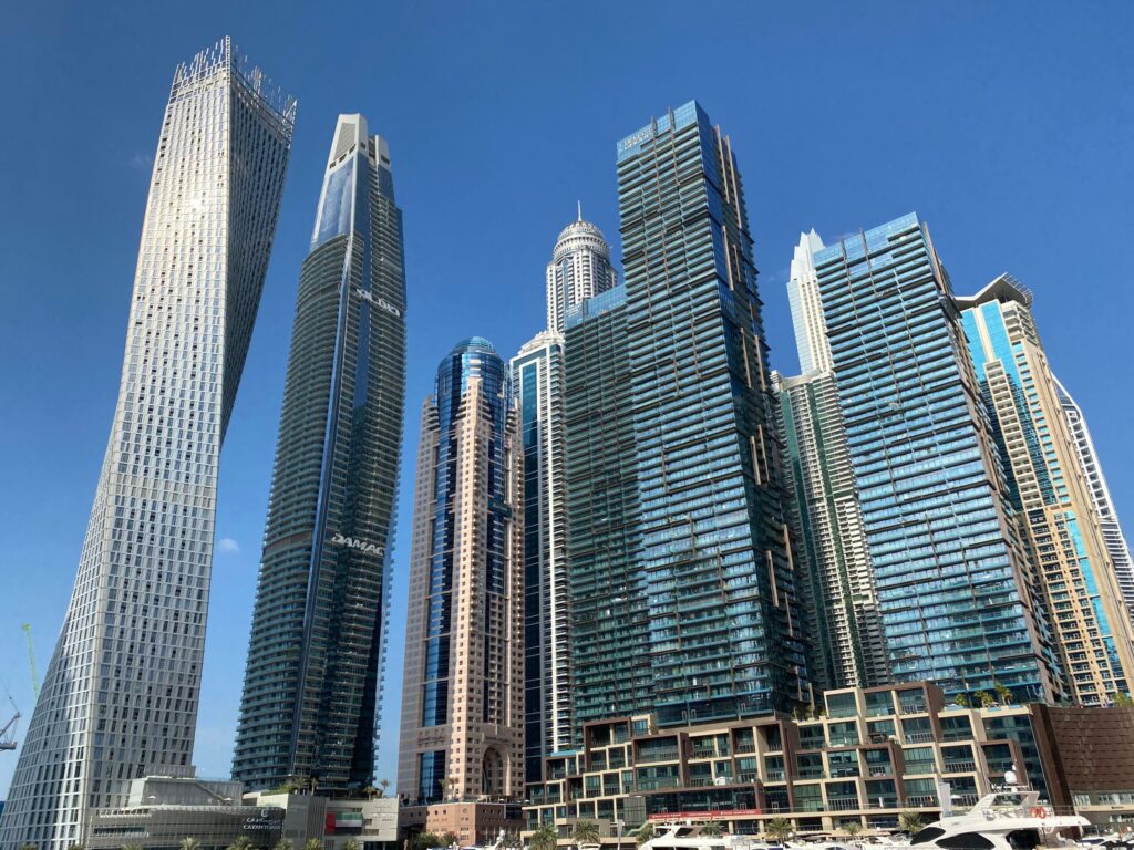 Glass residential towers rising against a blue sky in the Dubai Marina skyline