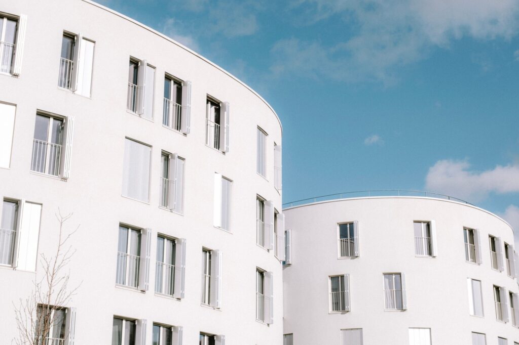 Curved white residential buildings with shuttered windows under a blue sky