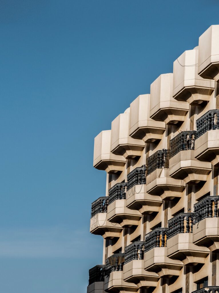 Close-up upward angle of a modern cream-toned high-rise apartment balcony facade against a clear blue sky in Dubai