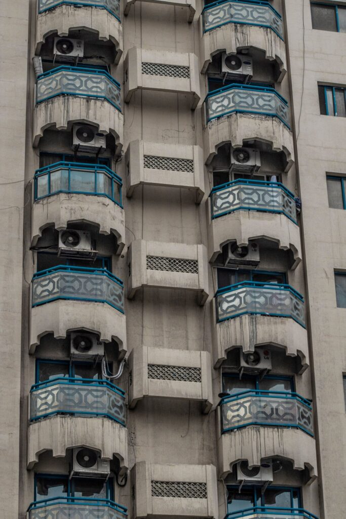 Concrete high-rise apartment building with distinctive balconies against a clear blue sky in Dubai