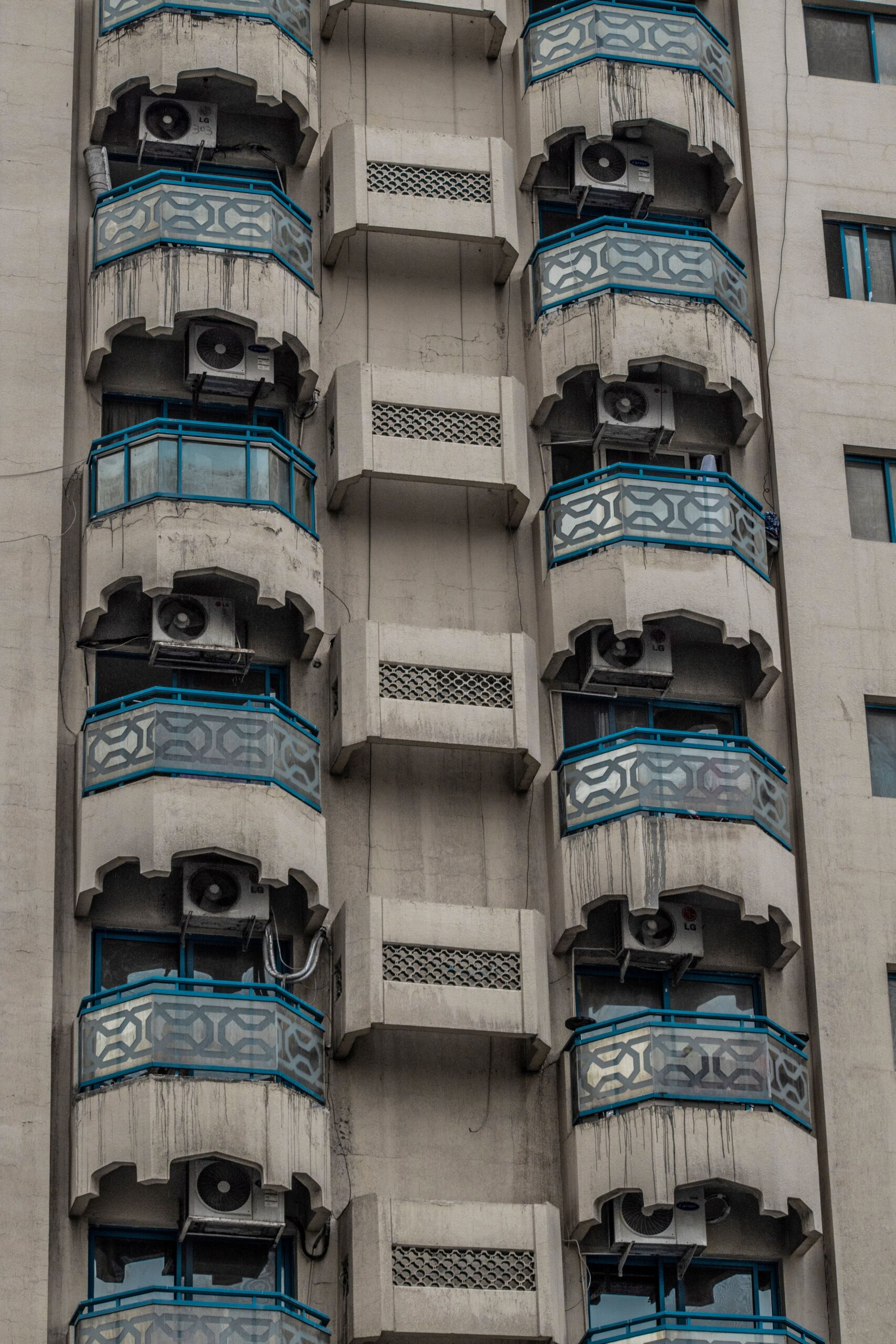 Concrete high-rise apartment building with distinctive balconies against a clear blue sky in Dubai
