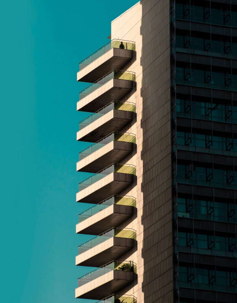 Tall modern high-rise apartment building with distinctive zigzag balconies against a clear blue sky in Dubai