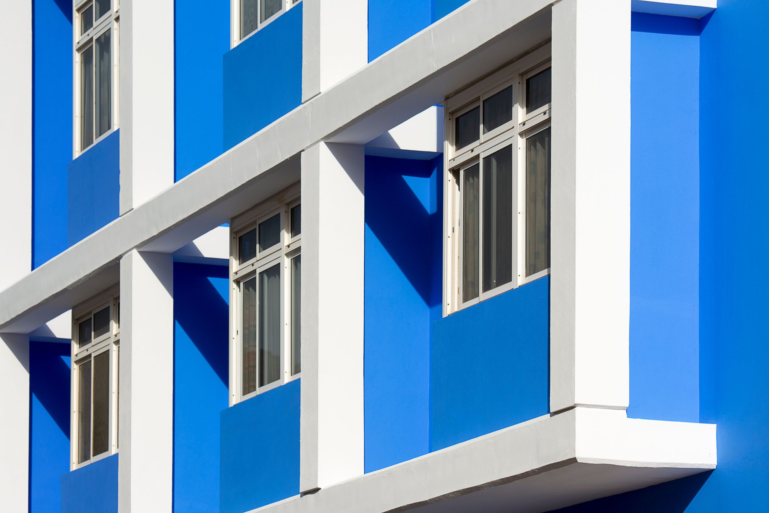 Close-up of a modern apartment building facade in vivid blue and white, representative of Mas Tower in Dubai Silicon Oasis, Dubai