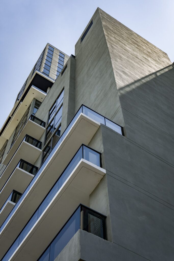 Low angle view of a modern cream apartment building corner with box balconies against a clear blue sky in Dubai