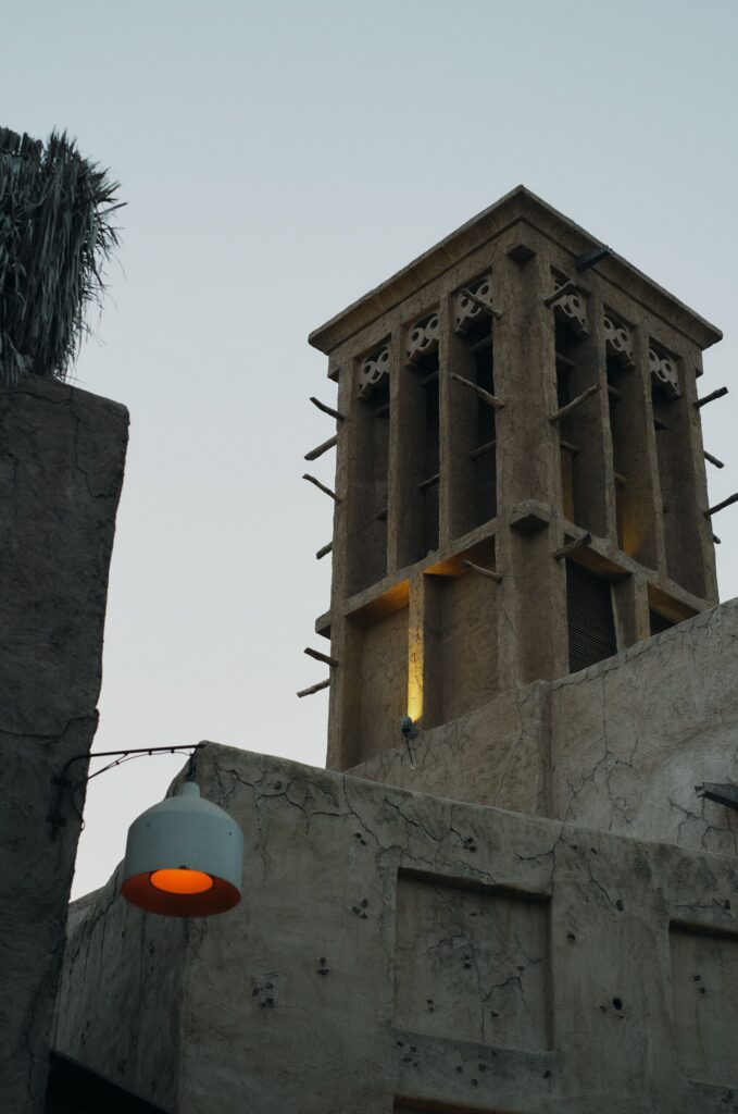 Traditional Arabian wind tower lit at dusk against a sandstone facade in Old Town, Downtown Dubai, near Reehan 4