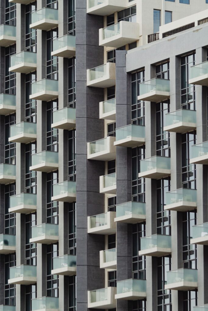 Close-up view of a modern mid-rise apartment building facade with glass balconies and large windows under natural light, representative of contemporary Dubai Studio City residential architecture