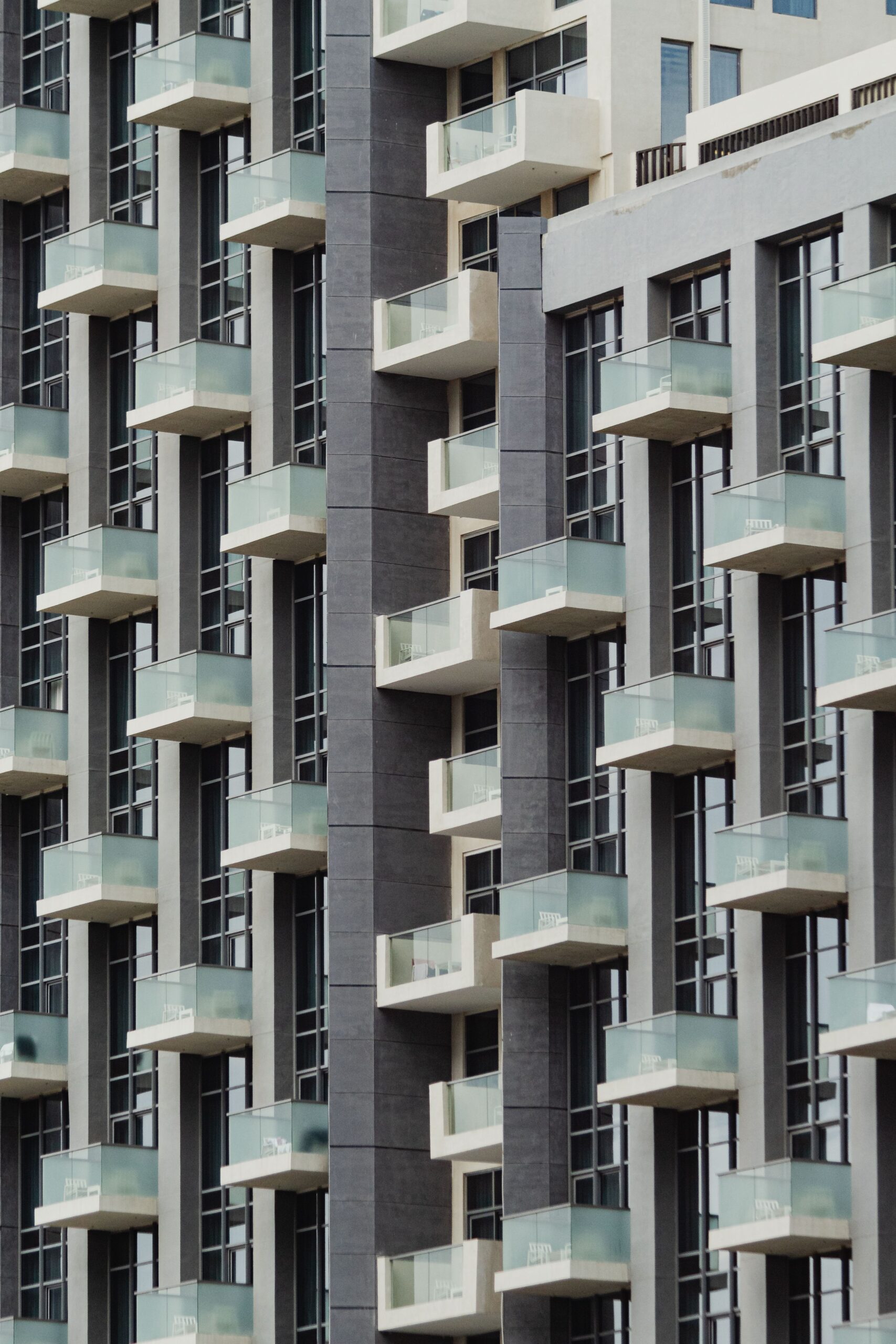 Close-up view of a modern mid-rise apartment building facade with glass balconies and large windows under natural light, representative of contemporary Dubai Studio City residential architecture