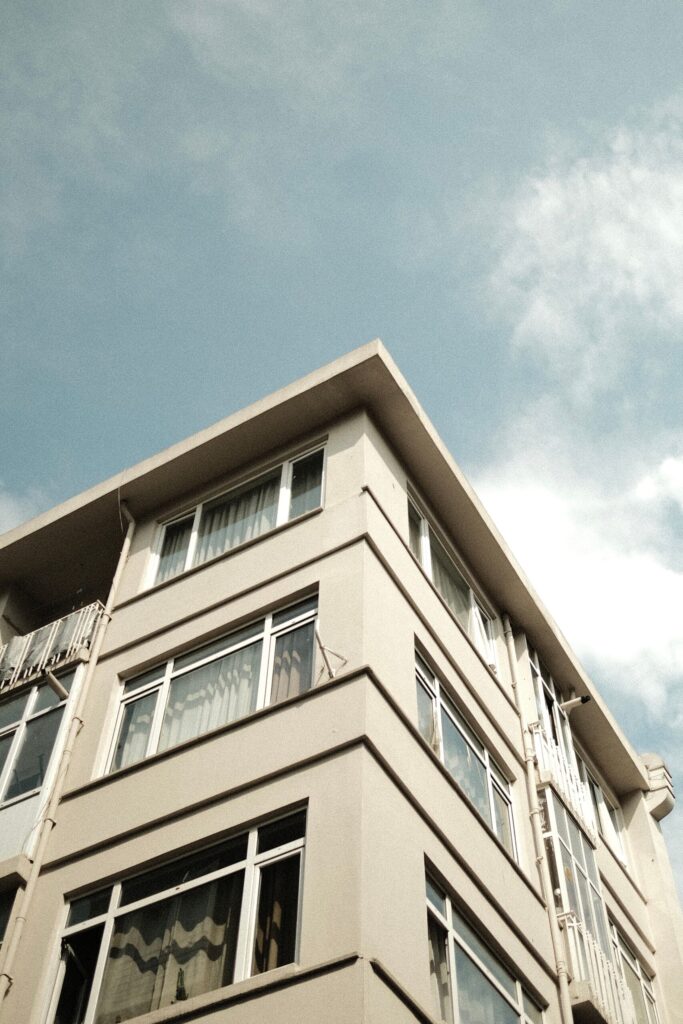 Modern cream-toned apartment building corner against a clear sky with light clouds in Dubai