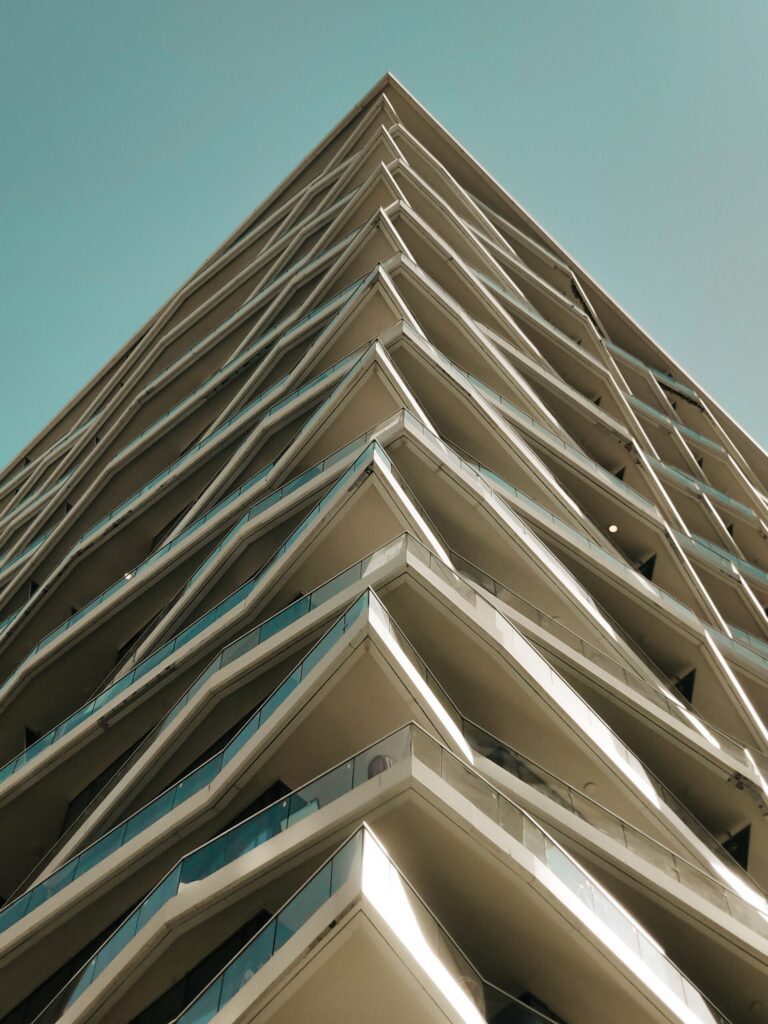 Low angle view of a modern high-rise tower corner with a geometric facade against a clear blue sky in Dubai