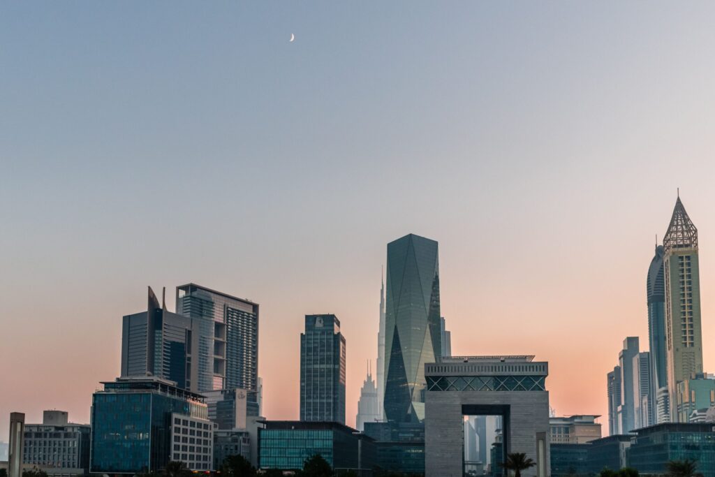 Dubai business district towers under a dusk sky with a crescent moon