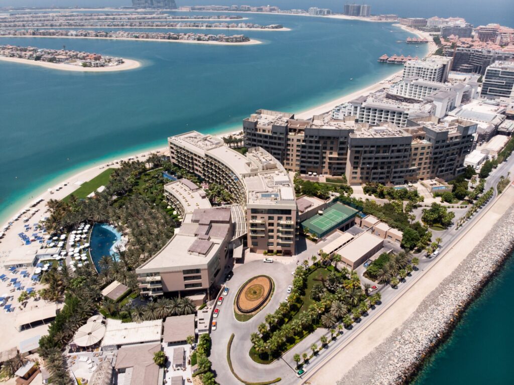 Aerial view of a curved, modern resort and apartment complex on Palm Jumeirah's East Crescent, near Armani Beach Residences