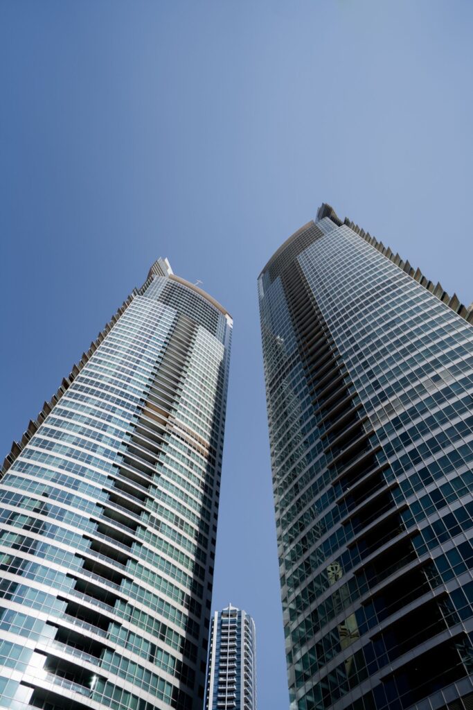 Low-angle upward view of glass high-rise towers converging toward a clear blue sky near Murjan 5, JBR