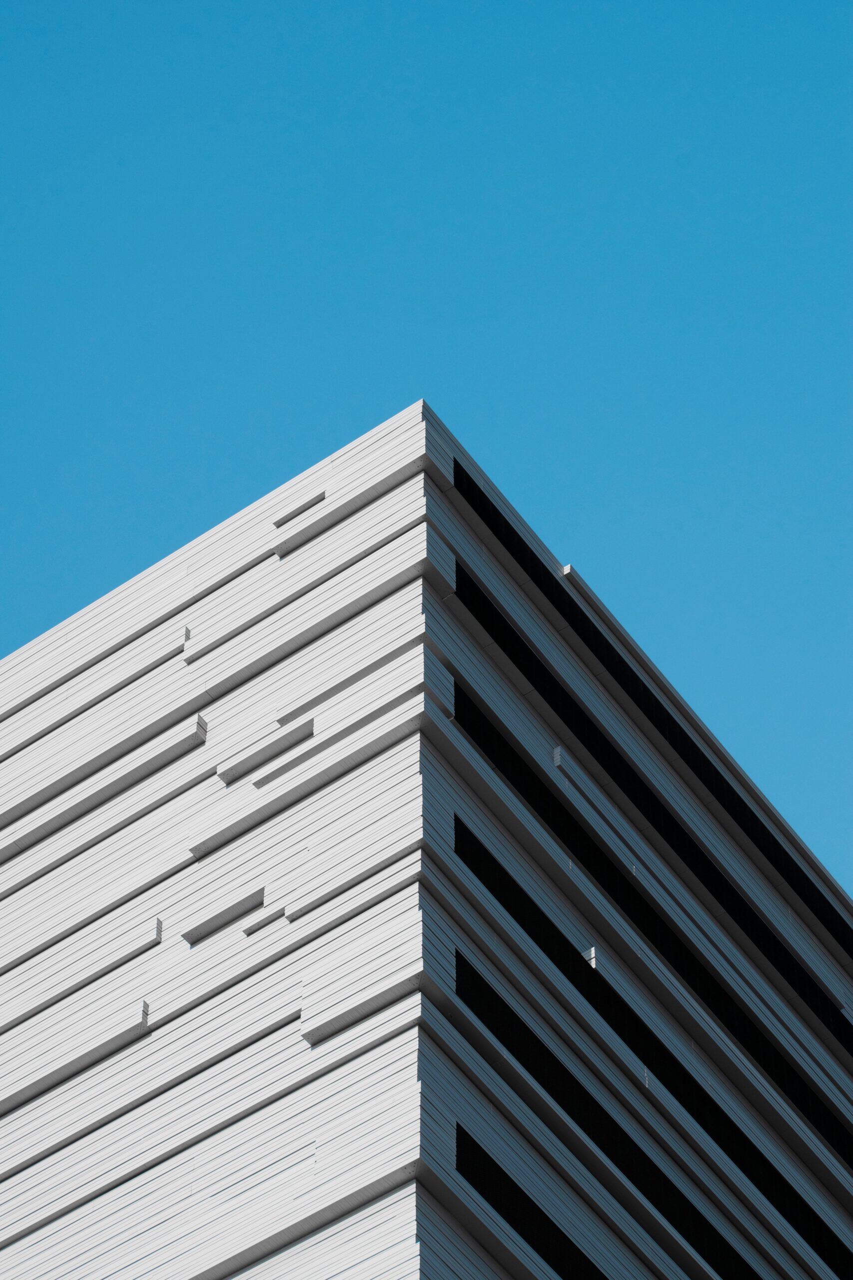 Sharp minimalist white building corner with subtle fluting against a deep blue sky in Dubai