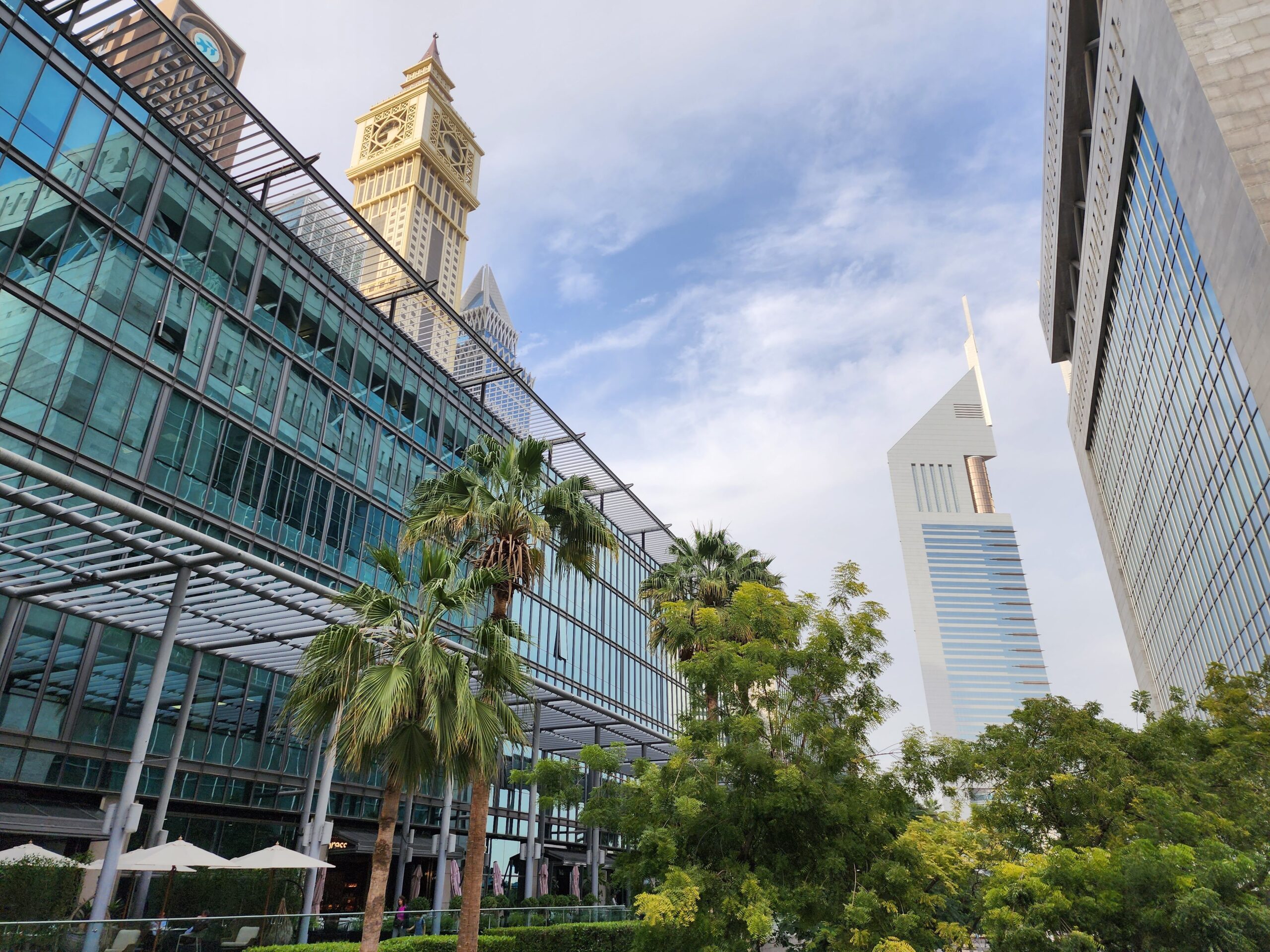 Daytime view of Dubai high-rise towers with palm trees in the foreground