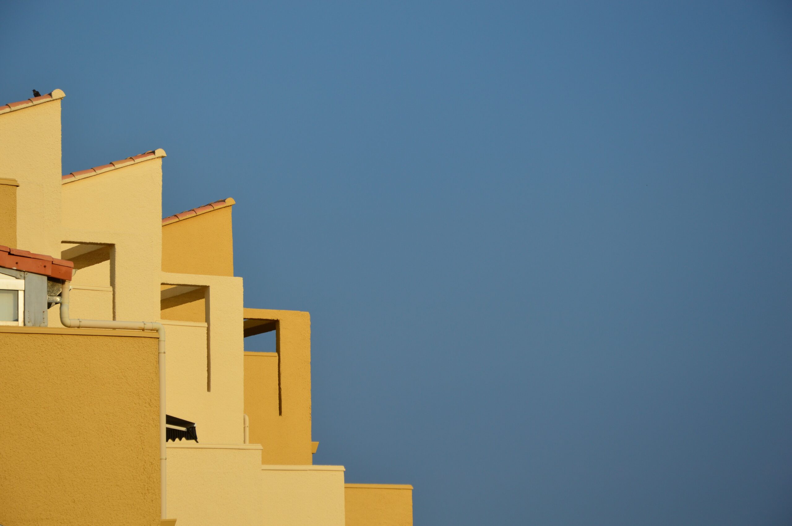 Sunlit sand-toned low-rise apartment facade with terracotta roof tiling, a Mediterranean-influenced architectural style typical of Dubai's Town Square community