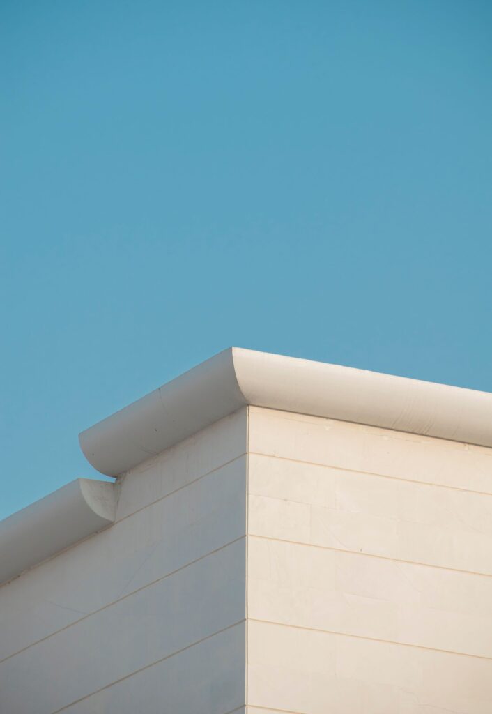 Minimalist white building corner with a curved roofline against a clear blue sky in Dubai