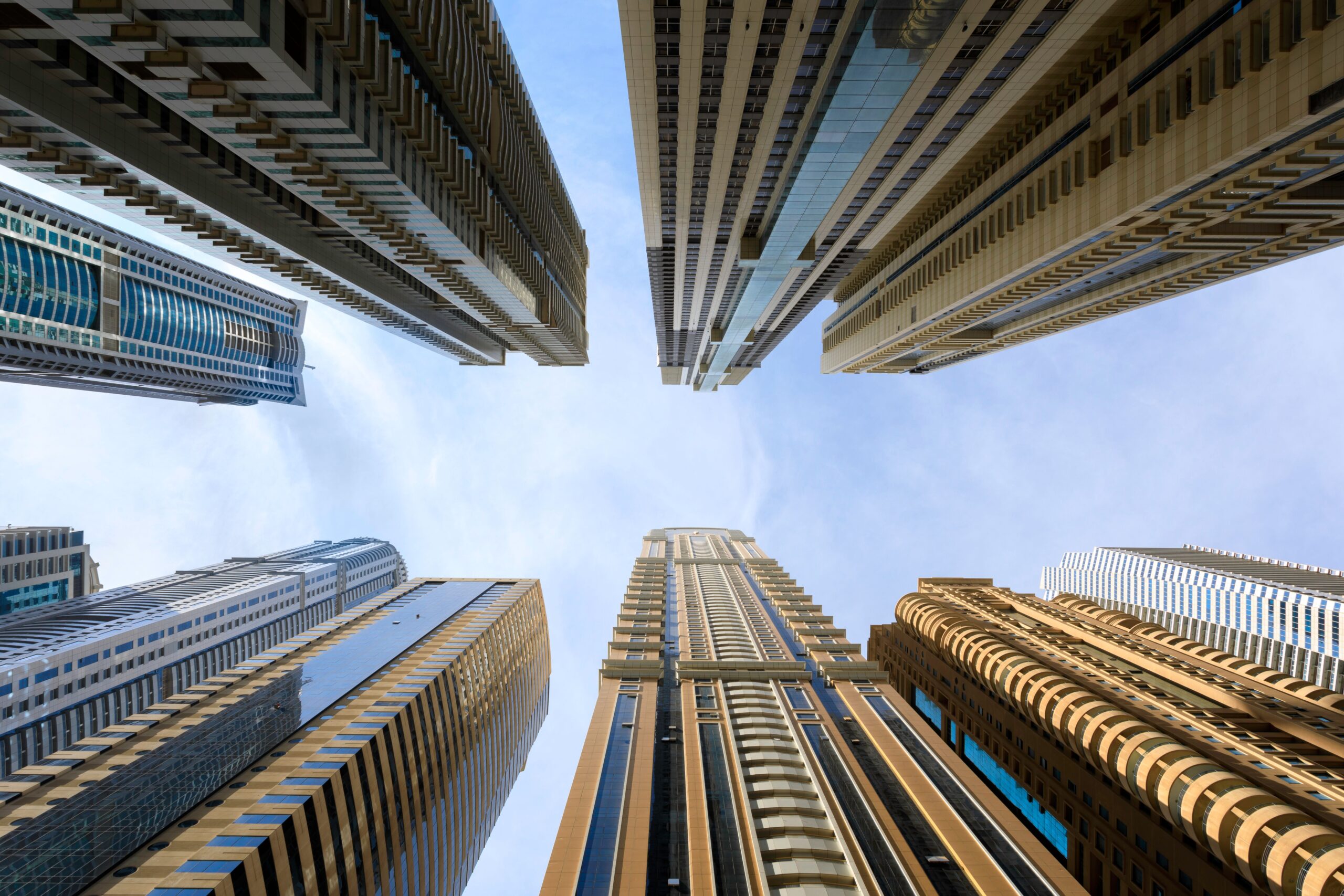Multiple modern glass high-rise towers converging upward against a clear sky in Downtown Dubai, near Bellevue Tower 2