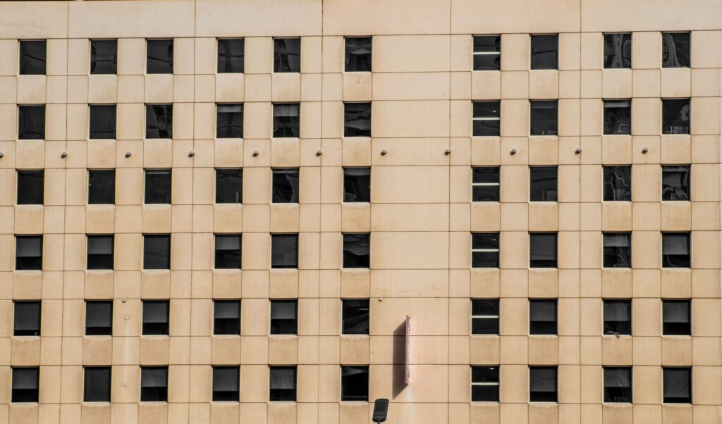 Rows of windows on a clean beige apartment building facade, representative of Chaimaa Avenue Residences in JVC, Dubai