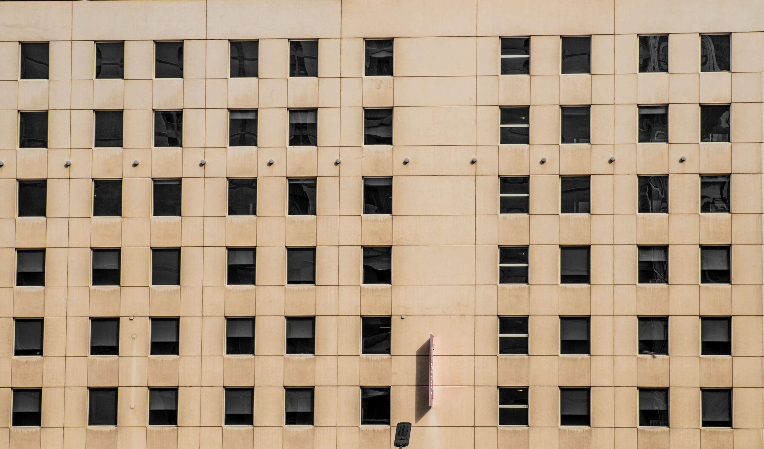Rows of windows on a clean beige apartment building facade, representative of Chaimaa Avenue Residences in JVC, Dubai
