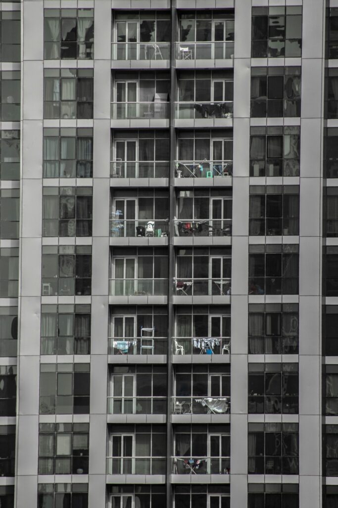 Vertical view of a contemporary apartment building facade with balconies, representative of Binghatti Gardens in Dubai Silicon Oasis, Dubai