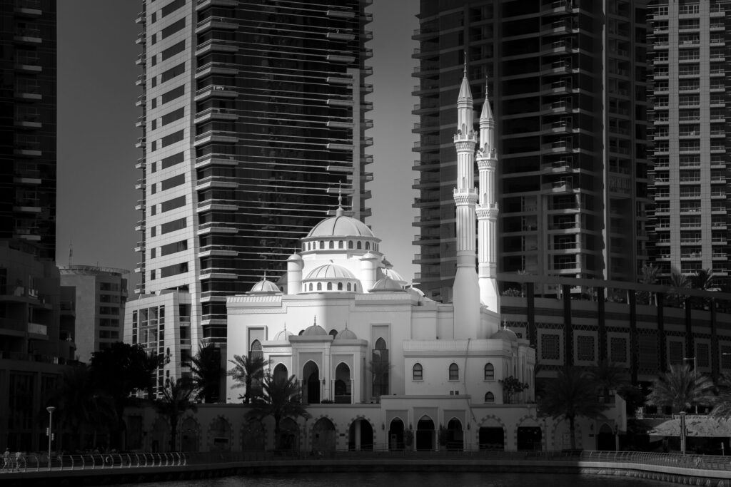 Black and white view of a mosque surrounded by skyscrapers in Dubai