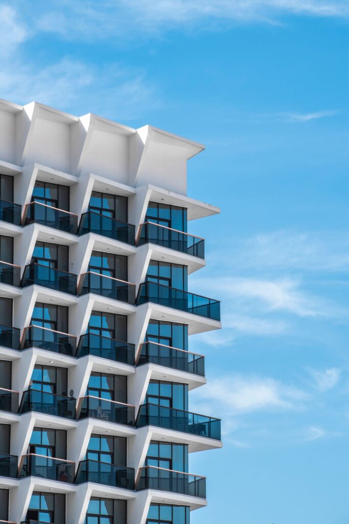 Modern mid-rise apartment building exterior in Dubai with geometric balconies against blue sky