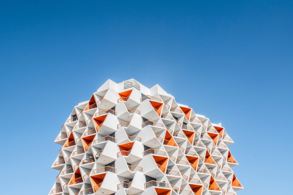 White apartment building with angular balconies against a clear blue sky