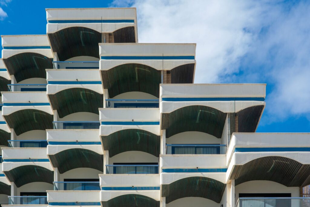 Modern white low-rise apartment building with stepped geometric balconies under a blue sky