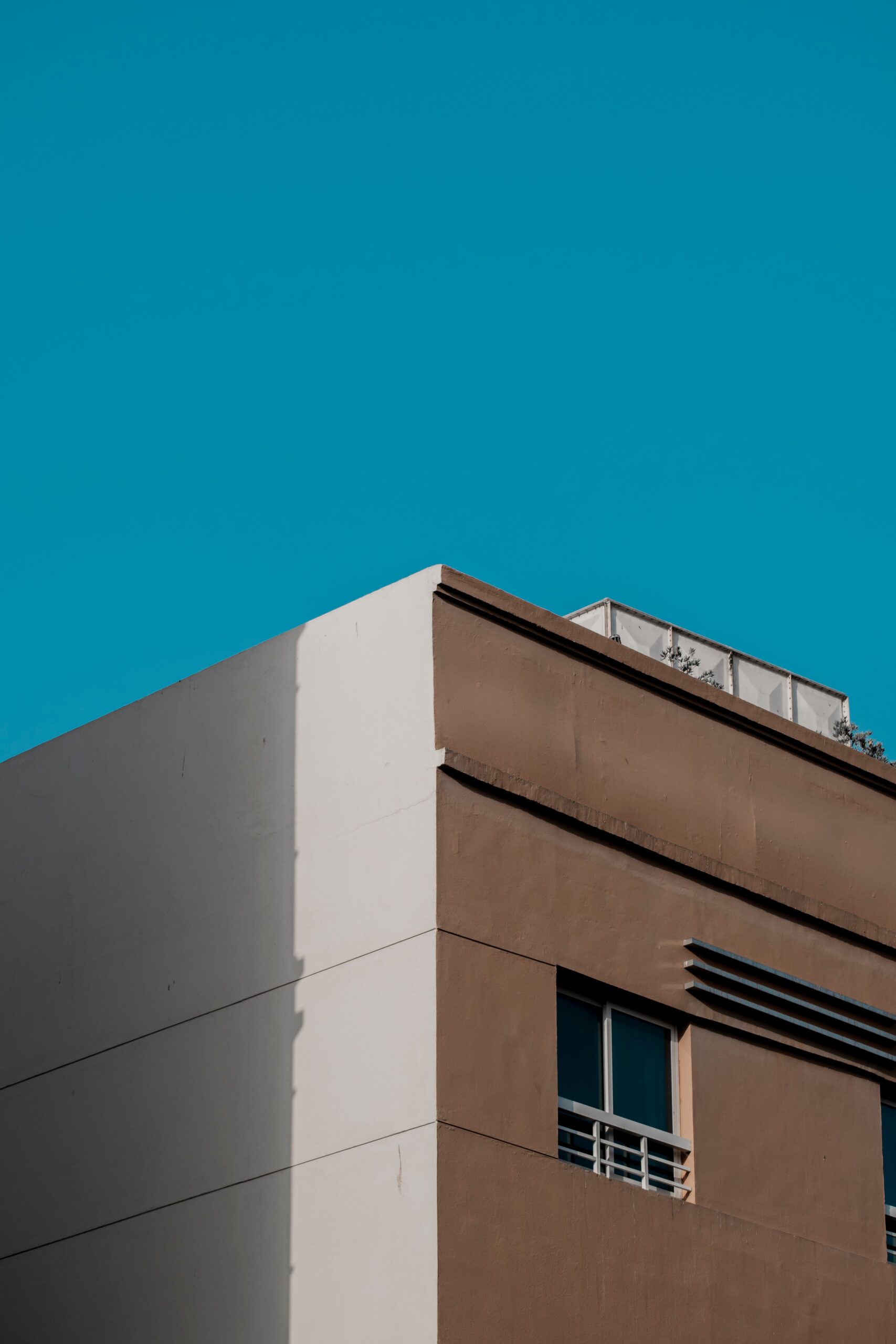 Minimalist beige and white apartment building corner against a deep blue sky, Dubai