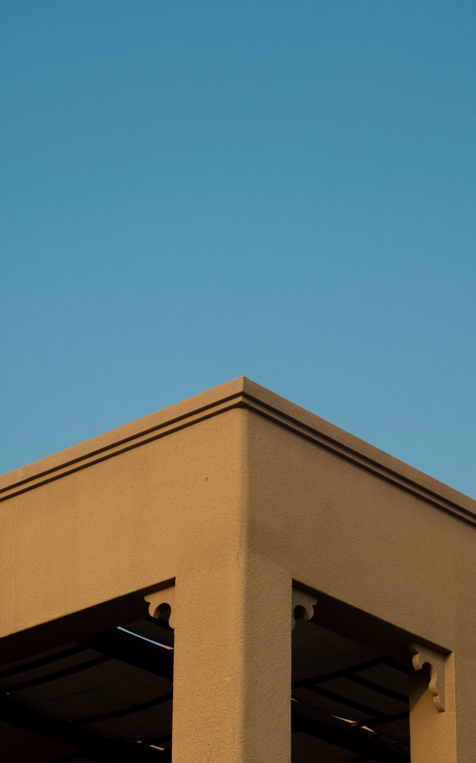 Minimalist tan-toned apartment building corner against a clear blue sky in Dubai